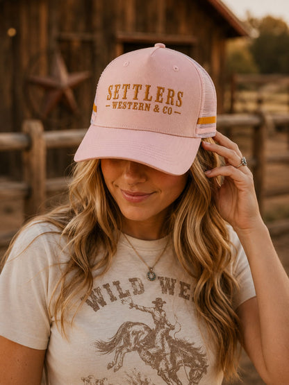Pink Settlers Western & Co trucker cap with golden embroidered wordmark and white mesh back